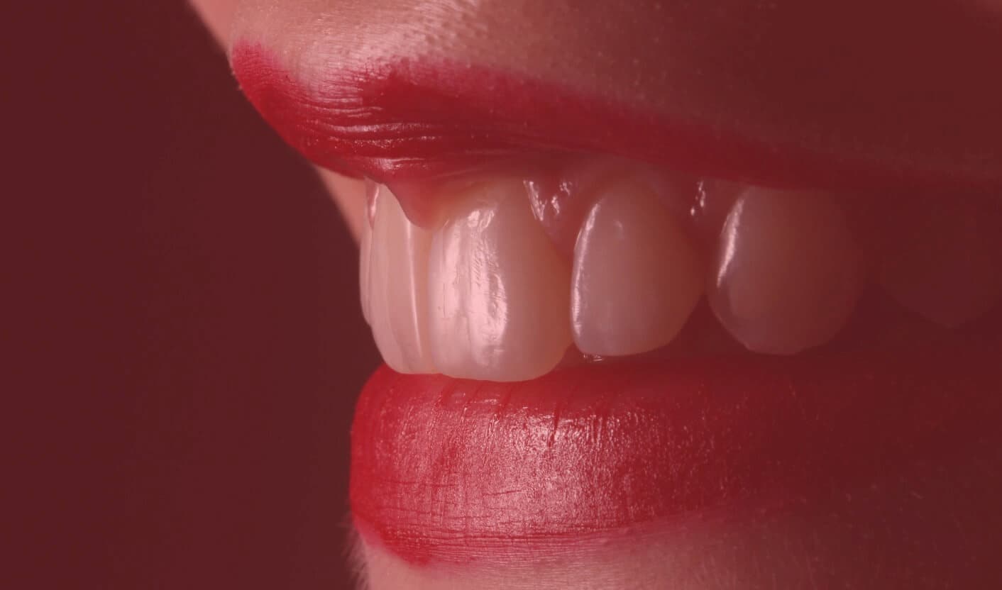 Nahaufnahme eines leicht geöffneten Mundes mit rot geschminkten Lippen und weißen Schneidezähnen